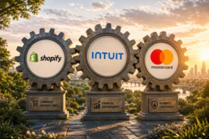 Three large interconnected gears displaying the logos of Shopify, Intuit, and Mastercard against a sunset cityscape; bases read 'Commerce Without Limits', 'Financial Empowerment', and 'Payments Everywhere'